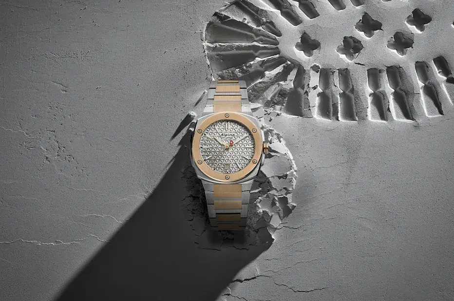 Dámské hodinky Alpina Alpiner Extreme Quartz AL-220S2AE2B s dvoubarevným náramkem na pozadí otisku trekové boty