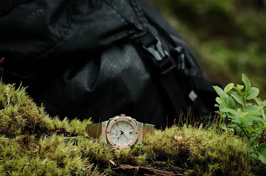 Dámské hodinky Alpina Alpiner Extreme Quartz AL-220S2AE2B v přírodním prostředí – stylový bicolor model na pozadí batohu a mechu