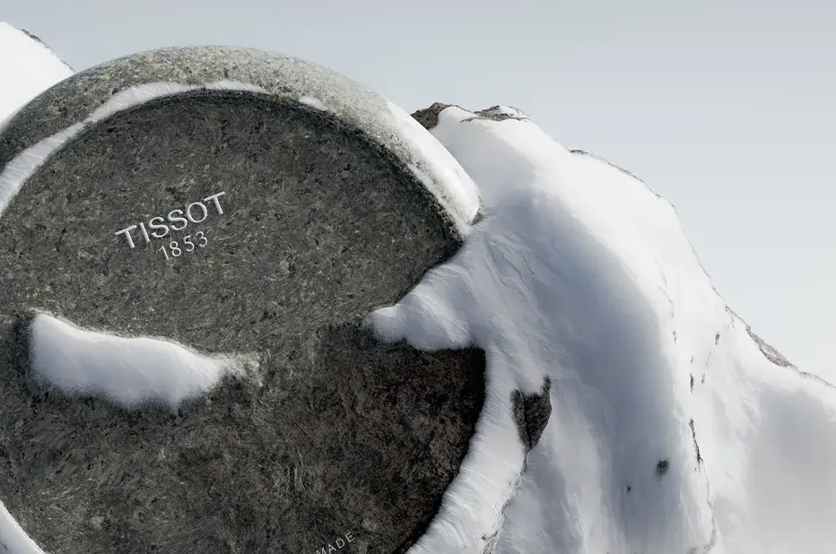 Logo Tissot 1853 vyryté v žule, symbolicky zasazené do alpského sněhu