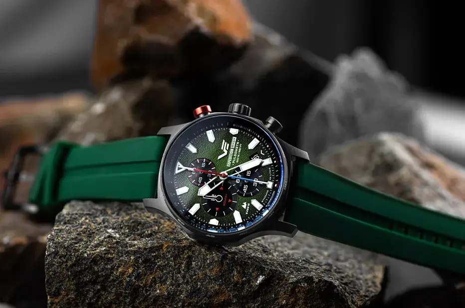Outdoorové pánské hodinky Vostok Europe Expedition Rysy VK67-592D499 na zeleném silikonovém řemínku, vystavené na pozadí skal